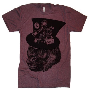 Puede incluir: Una camiseta color granate con un gráfico en blanco y negro de un gorila con un sombrero de copa con detalles de relojería.