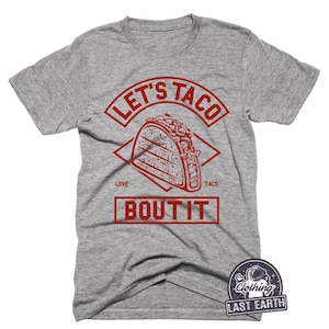 Puede incluir: Camiseta gris con un gr&aacute;fico rojo de un taco y el texto "Let's Taco Bout It".