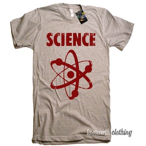 May include: A gray t-shirt with the word "SCIENCE" printed in red, with a red atom symbol underneath. The shirt is made of a soft, comfortable material.