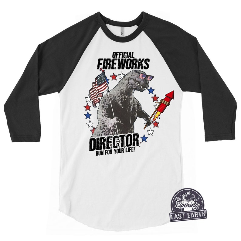 Puede incluir: Una camiseta de b&eacute;isbol blanca y negra con un gr&aacute;fico de un monstruo con gafas de sol y sosteniendo un fuego artificial. El texto "Official Fireworks Director Run For Your Life!" est&aacute; impreso en la camiseta.
