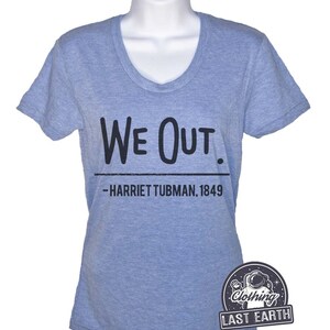 Puede incluir: Una camiseta azul claro con un gr&aacute;fico negro que dice "We Out. -Harriet Tubman, 1849".