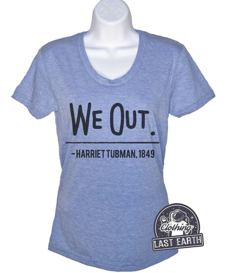 Puede incluir: Una camiseta azul claro con un gr&aacute;fico negro que dice "We Out. -Harriet Tubman, 1849".