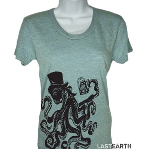 May include: A heather grey t-shirt with a black and white illustration of an octopus wearing a top hat and holding a beer mug. The octopus has eight tentacles and is in a celebratory pose. The text "LASTEARTH" is printed on the bottom right corner of the shirt.