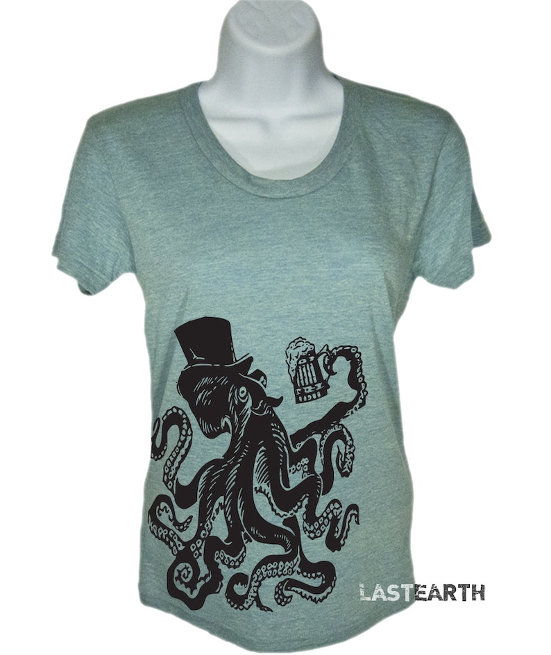 May include: A heather grey t-shirt with a black and white illustration of an octopus wearing a top hat and holding a beer mug. The octopus has eight tentacles and is in a celebratory pose. The text "LASTEARTH" is printed on the bottom right corner of the shirt.