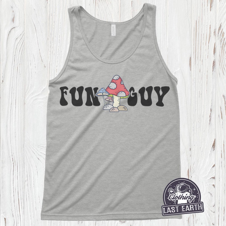 K&ouml;nnte beinhalten: Ein graues Tanktop mit dem Text "FUN GUY" in schwarzen Buchstaben mit einer Retro-Schrift. Unter dem Text befindet sich ein Cartoon-Bild von drei Pilzen. Die Pilze sind rot, wei&szlig; und blau.