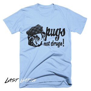 Puede incluir: Camiseta azul claro con una imagen en blanco y negro de un carlino con un sombrero y el texto "pugs not drugs!"
