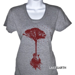May include: A gray t-shirt with a maroon tree design. The tree trunk is a guitar with roots at the bottom. The text "LASTEARTH" is printed on the bottom right corner of the shirt.