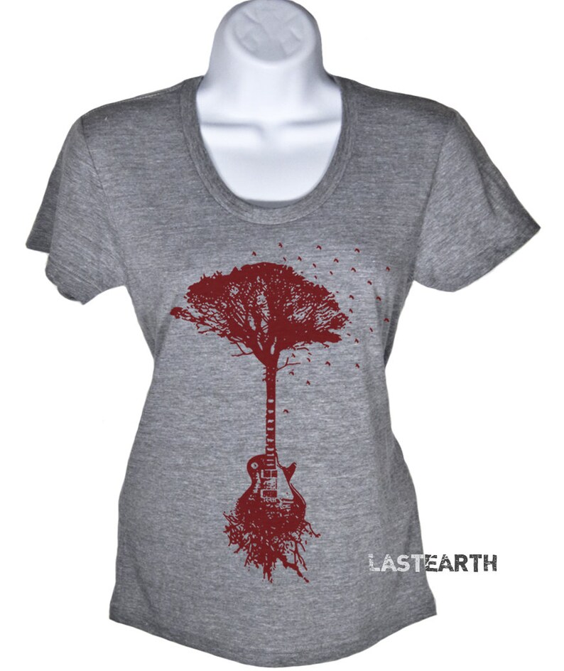 May include: A gray t-shirt with a maroon tree design. The tree trunk is a guitar with roots at the bottom. The text "LASTEARTH" is printed on the bottom right corner of the shirt.