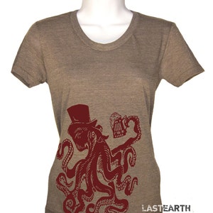 May include: A brown t-shirt with a red octopus wearing a top hat and holding a beer mug. The octopus has eight tentacles and is in a standing position. The text "LASTEARTH" is printed on the bottom right corner of the shirt.