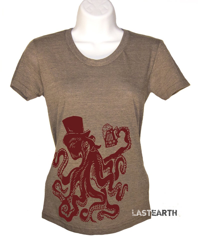 May include: A brown t-shirt with a red octopus wearing a top hat and holding a beer mug. The octopus has eight tentacles and is in a standing position. The text "LASTEARTH" is printed on the bottom right corner of the shirt.