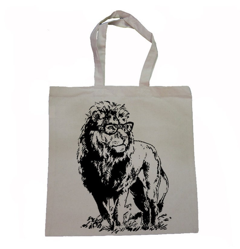 May include: A white canvas tote bag featuring a black and white illustration of a lion wearing glasses. The lion is looking to the right.