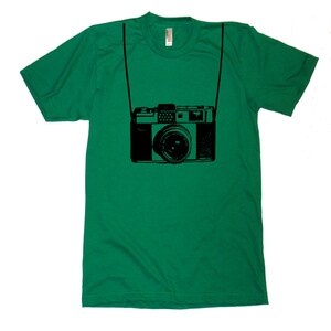 May include: A green t-shirt with a black graphic of a vintage camera with a strap.