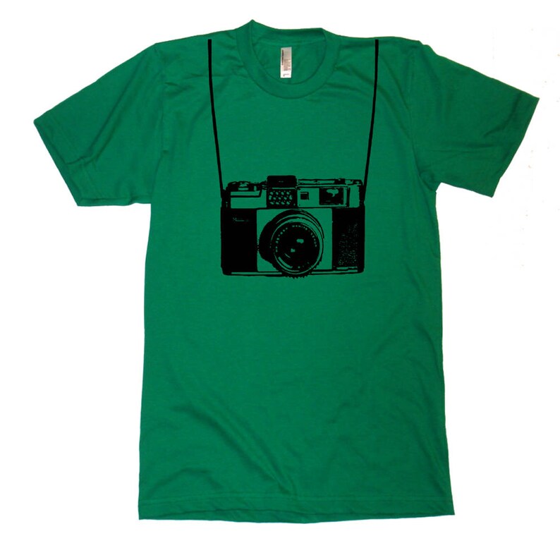 May include: A green t-shirt with a black graphic of a vintage camera with a strap.