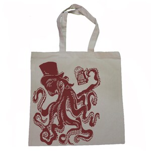 May include: A white canvas tote bag with a red illustration of an octopus wearing a top hat and holding a beer stein.