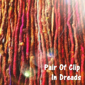 May include: A close-up of a bundle of colorful wool dreadlocks with beads. The dreadlocks are in various shades of red, orange, and brown. The text "Pair Of Clip In Dreads" is visible at the bottom of the image.