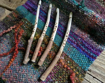 Un ganchillo hecho a mano, rústico, de madera natural y orgánica, con forma de rama de bosque tallada, ideal para recreaciones históricas y manualidades celtas.