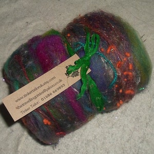 May include: A colorful, hand-crafted wool ball with a green ribbon and a business card attached. The card includes the website address www.tinkertailoruk.etsy.com, the email address thetravellingpixies@yahoo.co.uk, and the phone number 01686 669893. The card reads "Tinker Tailor".