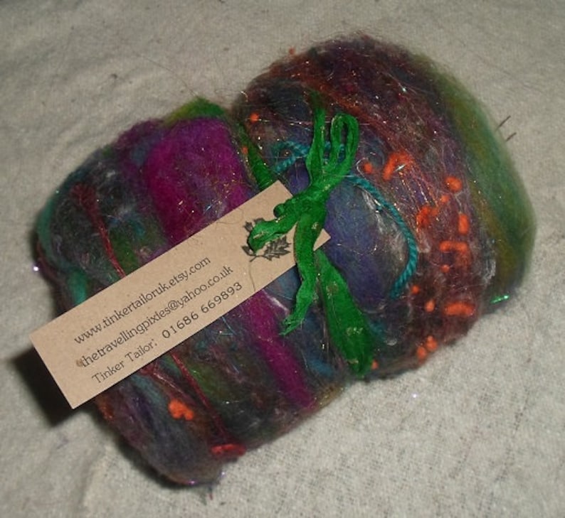May include: A colorful, hand-crafted wool ball with a green ribbon and a business card attached. The card includes the website address www.tinkertailoruk.etsy.com, the email address thetravellingpixies@yahoo.co.uk, and the phone number 01686 669893. The card reads "Tinker Tailor".