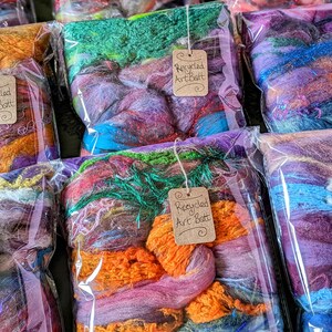 May include: A variety of colorful recycled art batts in clear plastic bags with brown paper tags that say "Recycled Art Batt".