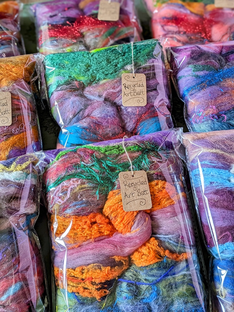 May include: A variety of colorful recycled art batts in clear plastic bags with brown paper tags that say "Recycled Art Batt".
