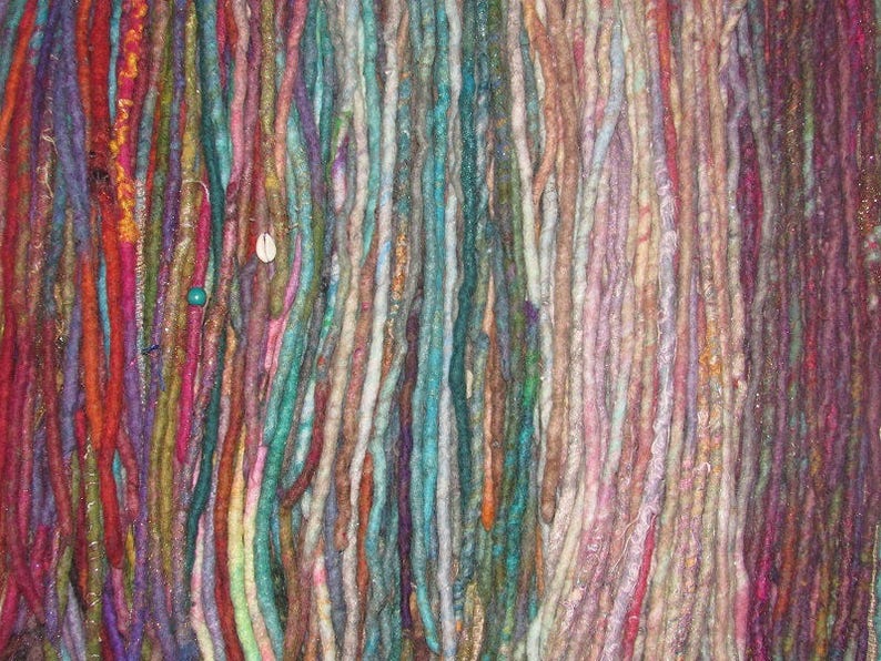 May include: A collection of colorful, hand-crafted dreadlocks made from wool yarn. The dreadlocks are arranged in a vertical row and feature a variety of colors, including red, blue, green, purple, and brown.