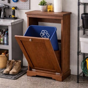 Op de afbeelding: Een houten recyclingbak met een scharnierende deur en een blauwe plastic container binnenin. De bak heeft een warme bruine kleur en een eenvoudig, klassiek ontwerp. De blauwe container heeft een recycling symbool.