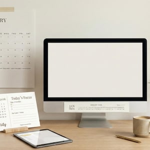 May include: A desk scene with a computer, tablet, mug, and pen. A wall calendar and a desk calendar are visible, both marked "January Clarity". A small vase with greenery is also present. The desk is made of wood.
