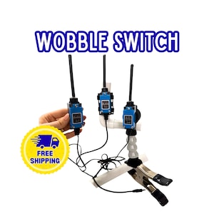 May include: Three blue wobble switches with black antennas and black cords. The switches are mounted on white PVC pipe structures, with one unit attached to a metal spring clamp. The text WOBBLE SWITCH is displayed in blue letters at the top.