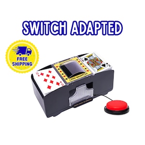 May include: An automatic card shuffler in a black plastic housing with two decks of playing cards inserted. The device features a yellow center panel labeled "AUTOMATIC CARD SHUFFLER" and is connected to a round red external push-button switch.