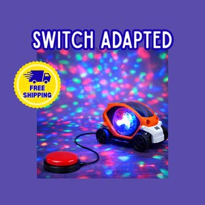 May include: Orange and white toy car with a light-up sphere inside, connected to a red button. The text "SWITCH ADAPTED" is above the car. A yellow sticker with "FREE SHIPPING" is also present.