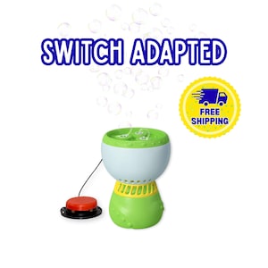 May include: A switch adapted bubble machine with a light blue and green body, a yellow vent section, and a red circular push button connected by a black cord. The text "SWITCH ADAPTED" appears above the device, and a yellow circular badge reads "FREE SHIPPING".