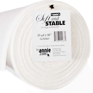 May include: A large roll of white Soft and Stable fabric stabilizer. A white paper label is attached to the front, displaying the text 'byannie's Soft and STABLE', '15 yd x 58" (white)', and contact information for byannie.com.