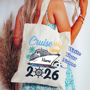 May include: Cream-colored tote bag with a cruise ship graphic. The design includes the words "Cruise Squad," a ship, palm trees, a sun, and the year "2026." The bag has a space to write a name.