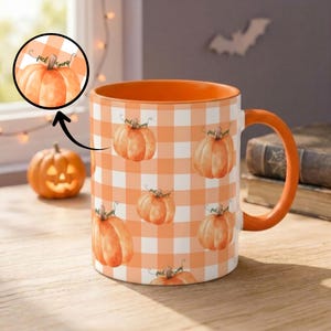 May include: A ceramic mug featuring an orange and white gingham pattern with watercolor-style pumpkin illustrations. The mug has an orange interior and handle. A circular inset shows a pumpkin with the text "fuck trump" written on it.