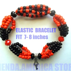 May include: Elastic bracelet with red and black beads. The bracelet fits wrists 7-8 inches. The bracelet has a key charm and the text "ELASTIC BRACELET FIT 7-8 inches".