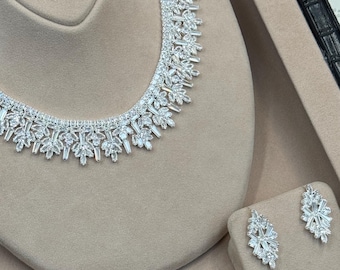 Conjunto de joyas nupciales con circonitas cúbicas florales: collar, pendientes, pulsera y anillo.