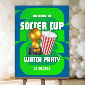 以下が含まれることがあります： サッカー観戦パーティーのイーゼルに立てられた看板。看板には「Welcome to Soccer Cup Watch Party」と書かれており、金色のトロフィーとストライプのカップのグラフィックが描かれています。「06.20.2026」の日付も表示されています。背景には白い風船があります。