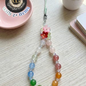 May include: A colorful beaded phone charm with a rainbow gradient of beads. The charm features a floral accent and a silver clasp. The text on the image says "20% EXTRA OFF with 2+ items" and "Grace Glow Workshop".