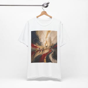 May include: White t-shirt with an abstract painting in gold, red, and black. The artwork shows a torch, rings, and figures, creating a dynamic design. The t-shirt is displayed on a wooden hanger, ready for wear.