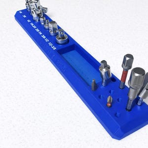 May include: A blue tool organizer with various sockets and bits. The organizer has labeled slots for different sizes and a central trough. The tools are silver and black, arranged neatly.
