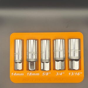 May include: An orange tray holds five chrome sockets of varying sizes: 14mm, 18mm, 5/8", 3/4", and 13/16". The text "METRIC & SAE" is printed on the tray. The sockets are for automotive or mechanical use.