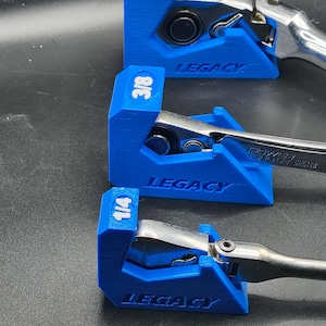 May include: Three blue wrench holders with the word "LEGACY" printed on them. Each holder has a different size marked on it: 1/2, 3/8, and 1/4. The holders are holding silver wrenches.