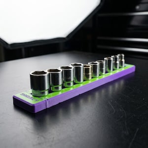 May include: A set of chrome sockets in various sizes, arranged on a purple and green holder. The holder has the word "SRGACY" printed on it. The sockets are designed for mechanical work.