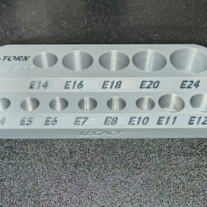 May include: A silver E-TORX socket organizer with two rows of circular holes labeled with sizes E4 through E24. The word "LEGACY" is printed on the bottom.