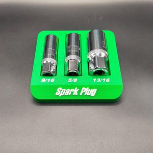 May include: A green spark plug socket holder with three sockets. The sockets are labeled 9/16, 5/8, and 13/16. The text "Spark Plug" is printed on the holder.
