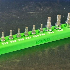 May include: A set of star-shaped Torx bits in a bright green holder. The holder is labeled "Legacy" and has sizes T8 through T50. The bits are made of metal and are arranged in ascending order.
