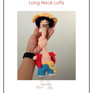 May include: A handmade crochet doll of the character Luffy from One Piece, with an elongated neck. The doll wears a straw hat, red jacket, blue shorts, and a yellow sash. The text "Long Neck Luffy" is at the top.