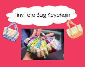 Pode incluir: Uma coleção de chaveiros de mini bolsas tote de crochê coloridas. Cada bolsa pequena apresenta uma combinação de cores única, incluindo azul, verde, amarelo e vermelho. O texto "Tiny Tote Bag Keychain" é exibido em um fundo rosa.