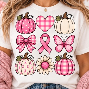 Op de afbeelding: Een wit t-shirt met een raster van negen roze en crèmekleurige afbeeldingen, waaronder pompoenen met stippen, ruitpatronen en lintmotieven, een roze geruit hart, een roze strik, een roze bewustzijnslint, een vlinder en een zonnebloem.