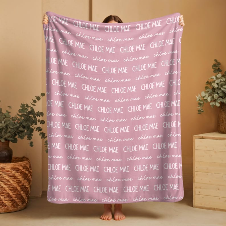 Puede incluir: Una manta suave de color rosa empolvado con un patr&oacute;n repetitivo del nombre Chloe Mae impreso en blanco. El texto alterna entre una fuente sans-serif en negrita en may&uacute;sculas y una delicada fuente cursiva en min&uacute;sculas por toda la tela.